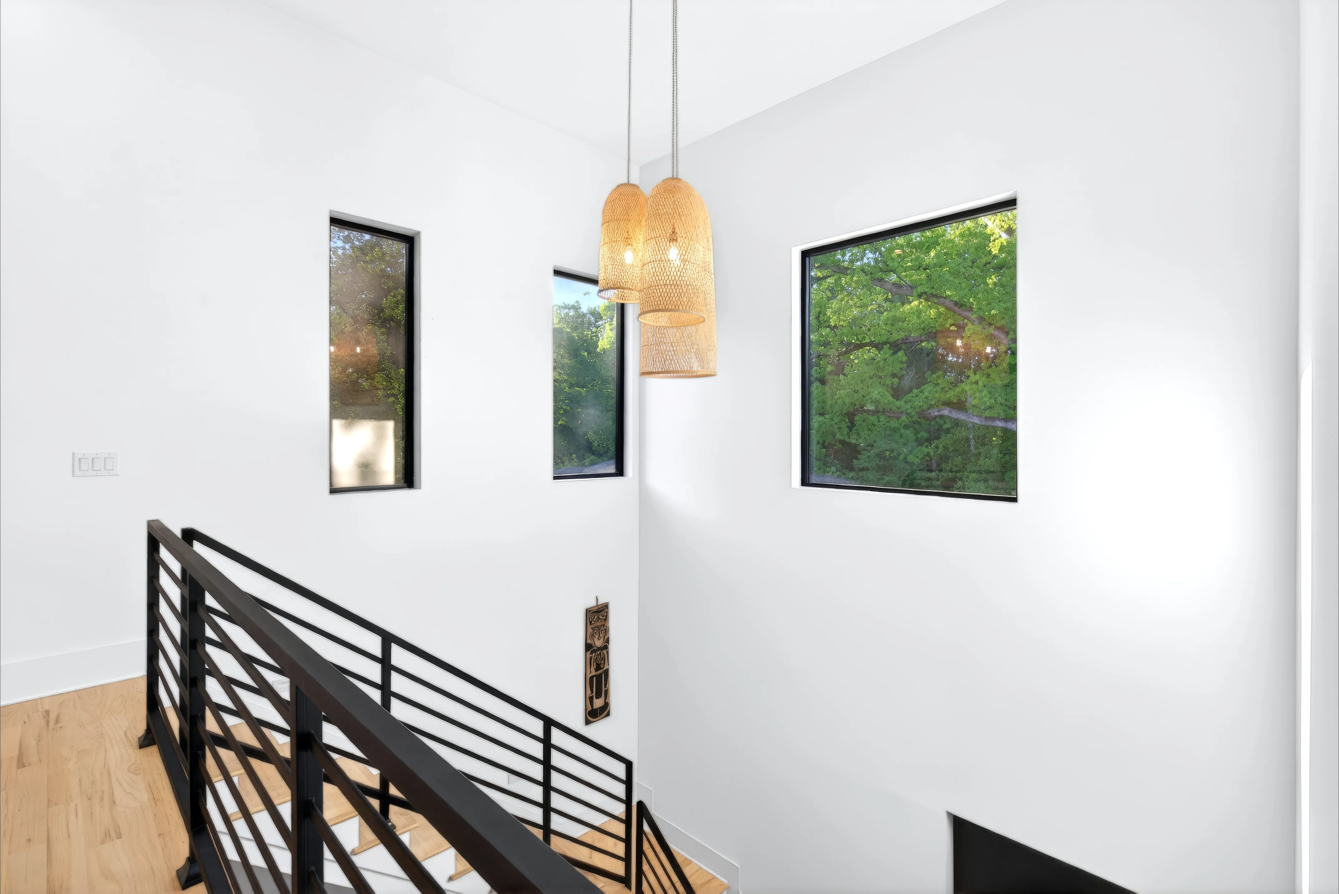 Upstairs landing with a black metal railing and pendant lights