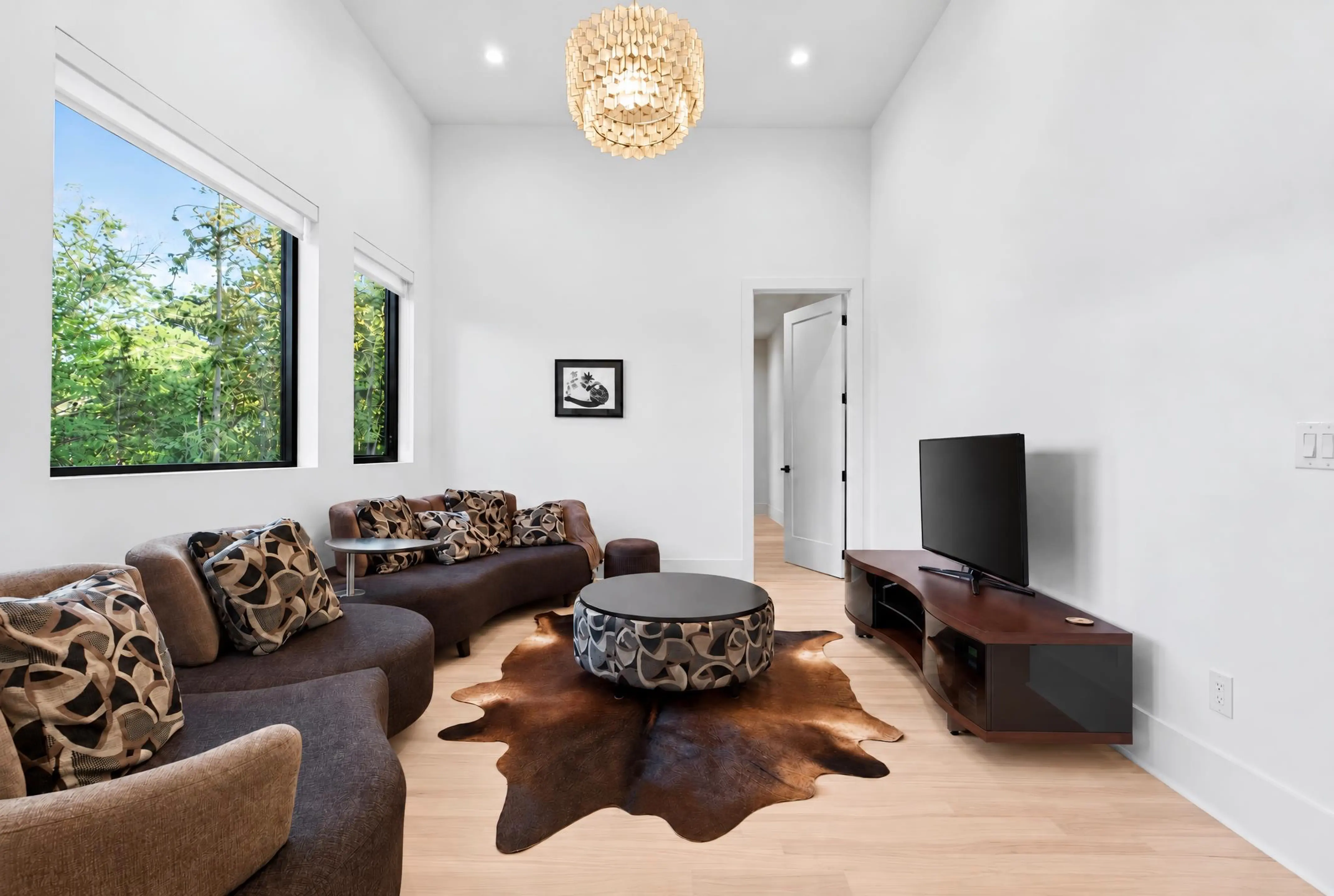 Living room with a sectional, cowhide rug, and tall windows