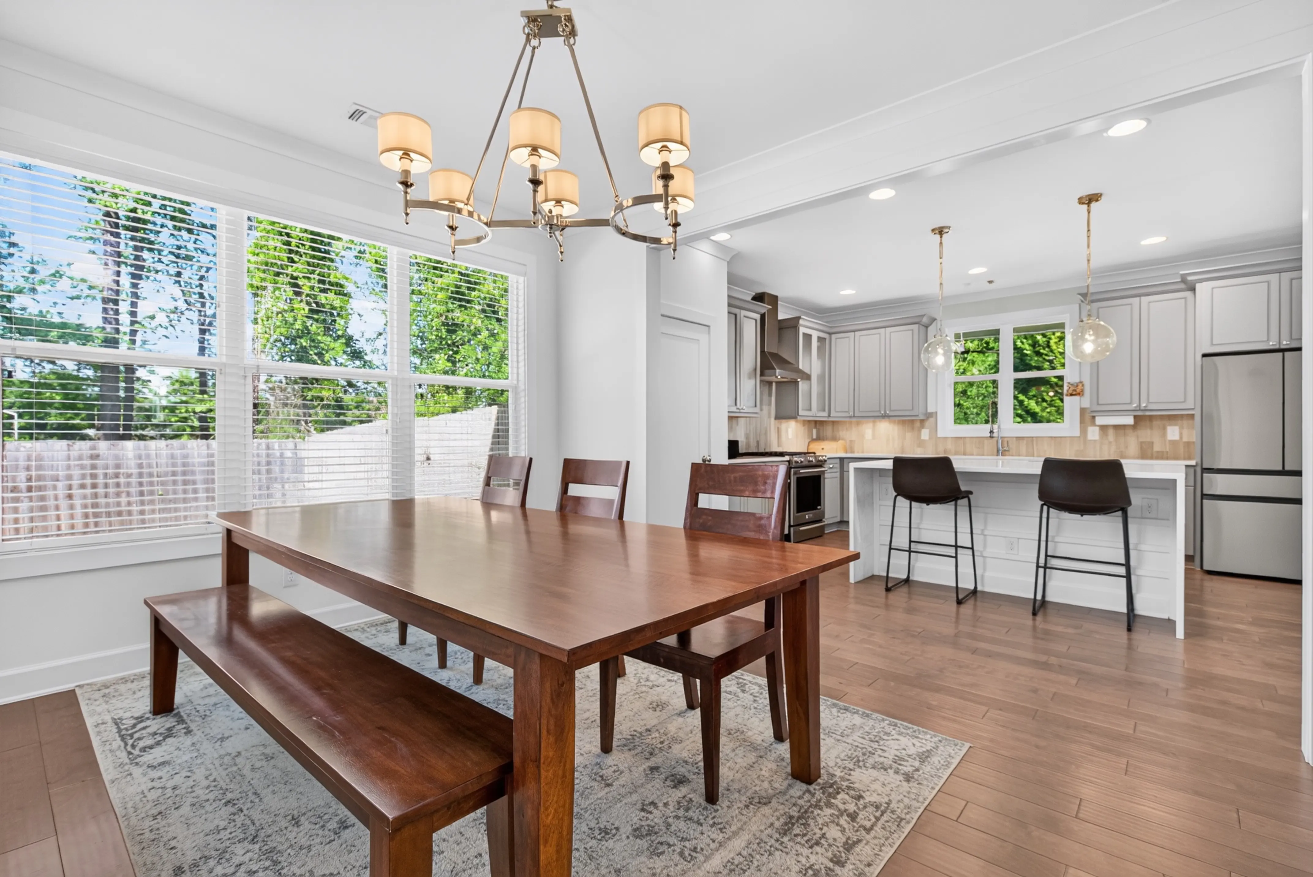 Dining table beside a bright white kitchen with an island