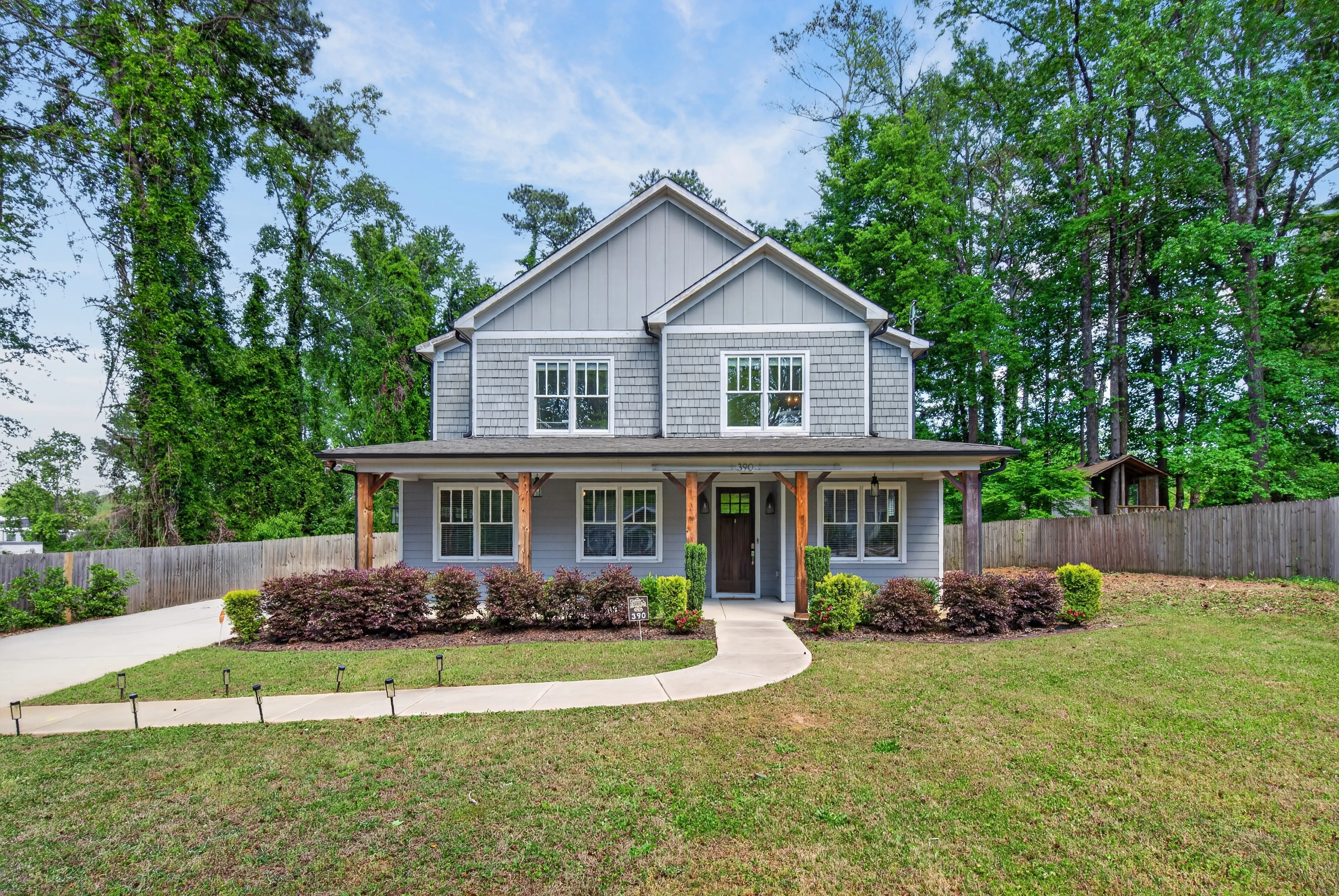 Front view of a two-story gray farmhouse-style home with a wide porch