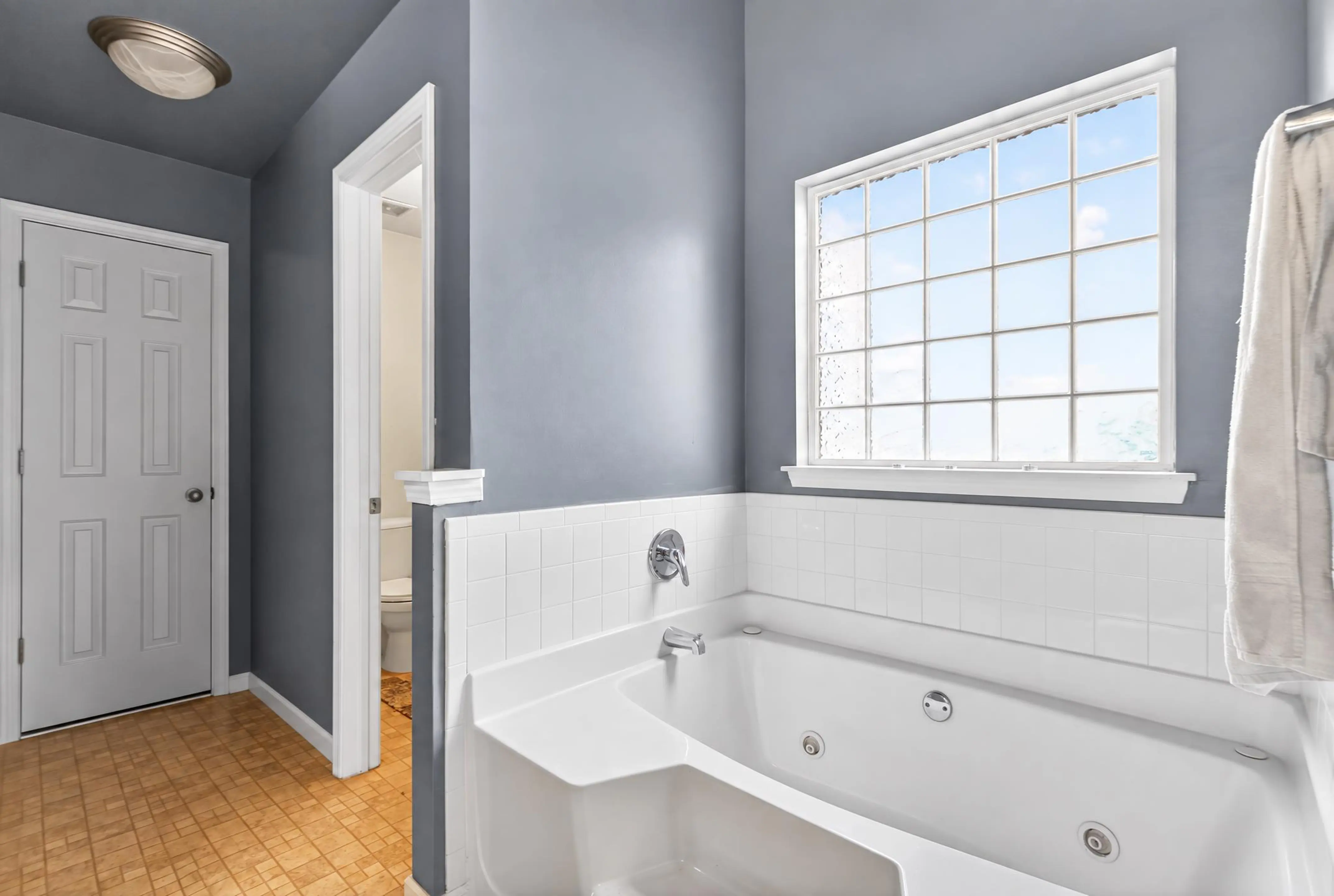Bathroom with a jetted tub beneath a large window