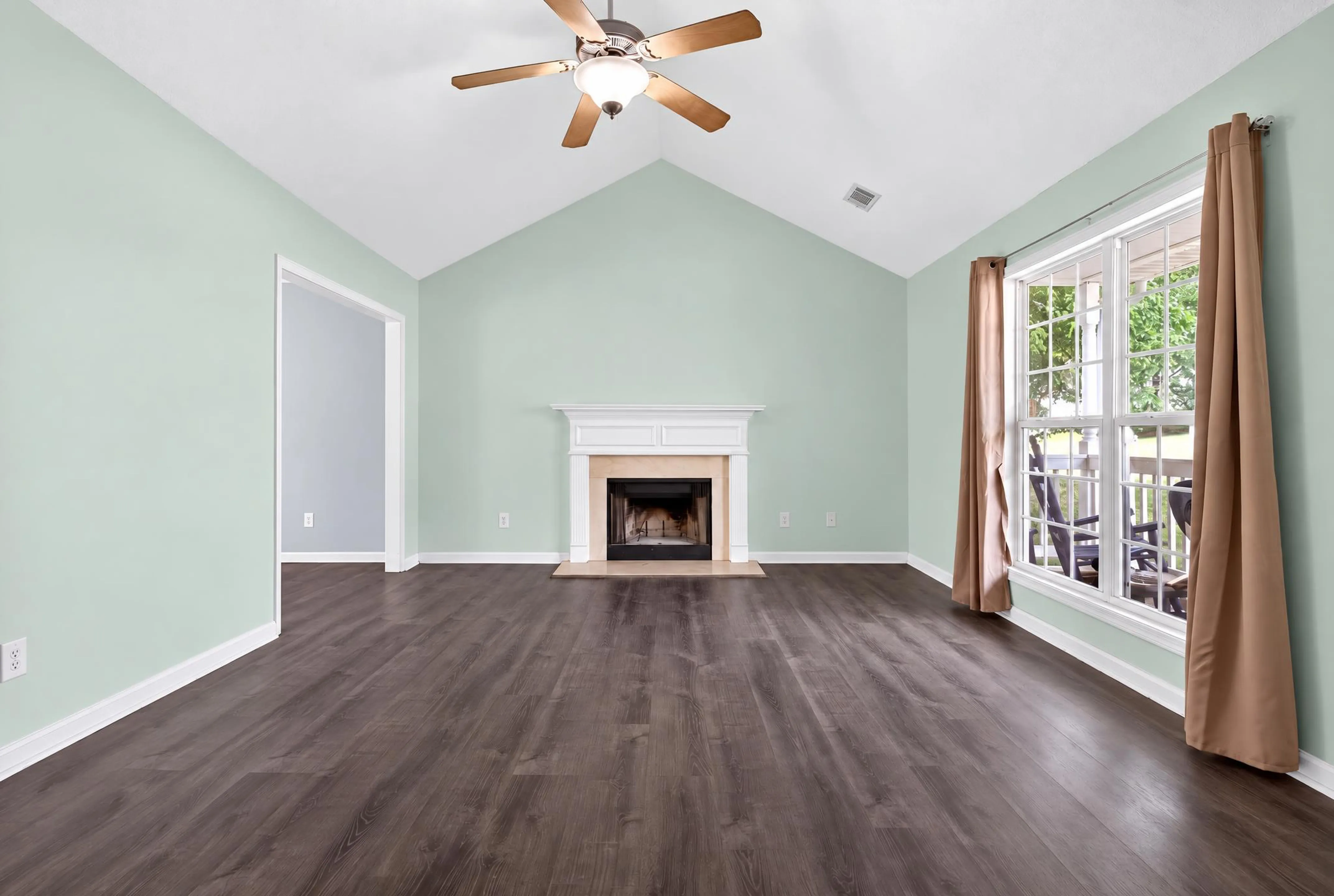 Living room with sage walls, a fireplace, and a vaulted ceiling