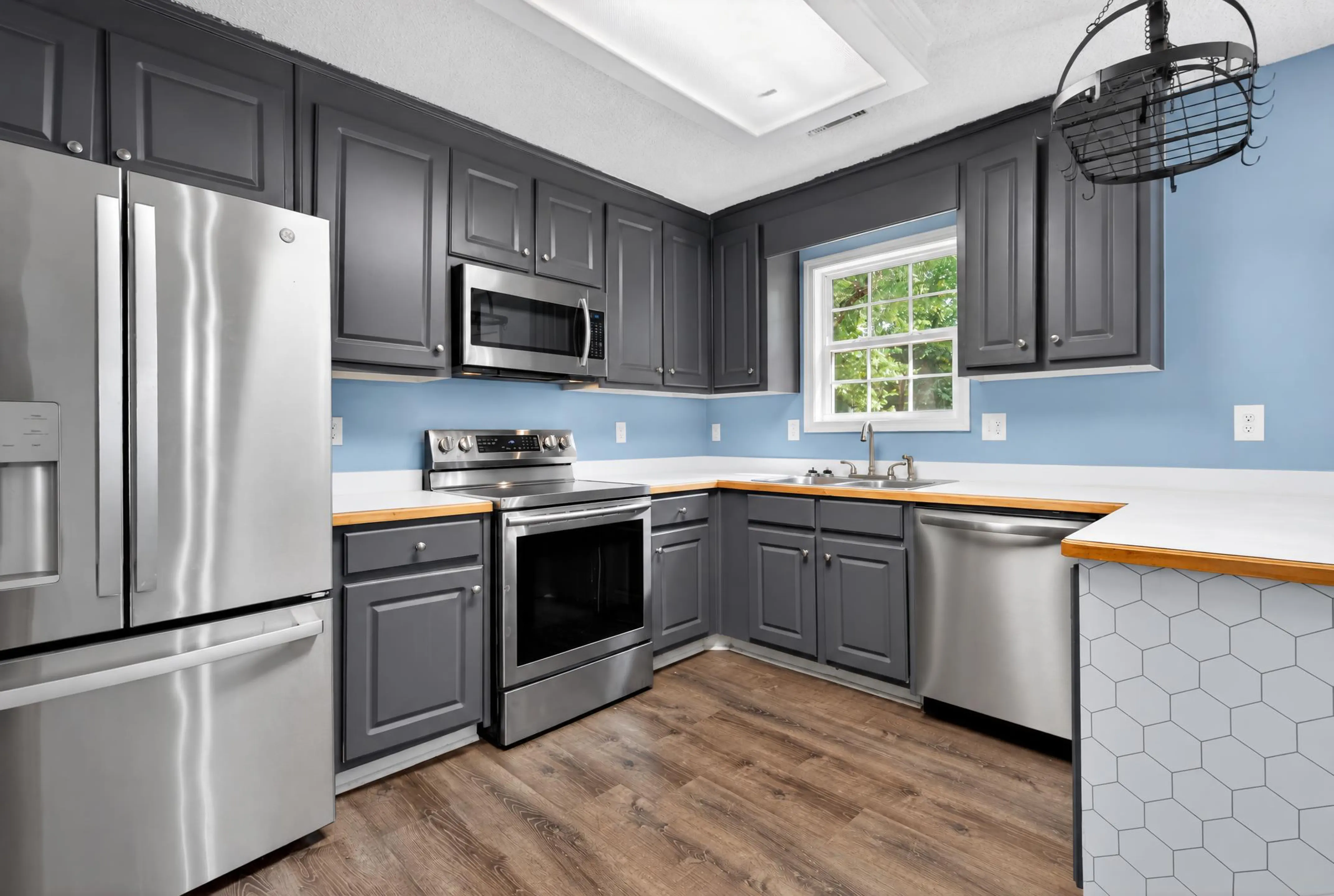 Kitchen with dark gray cabinets, blue walls, and stainless appliances