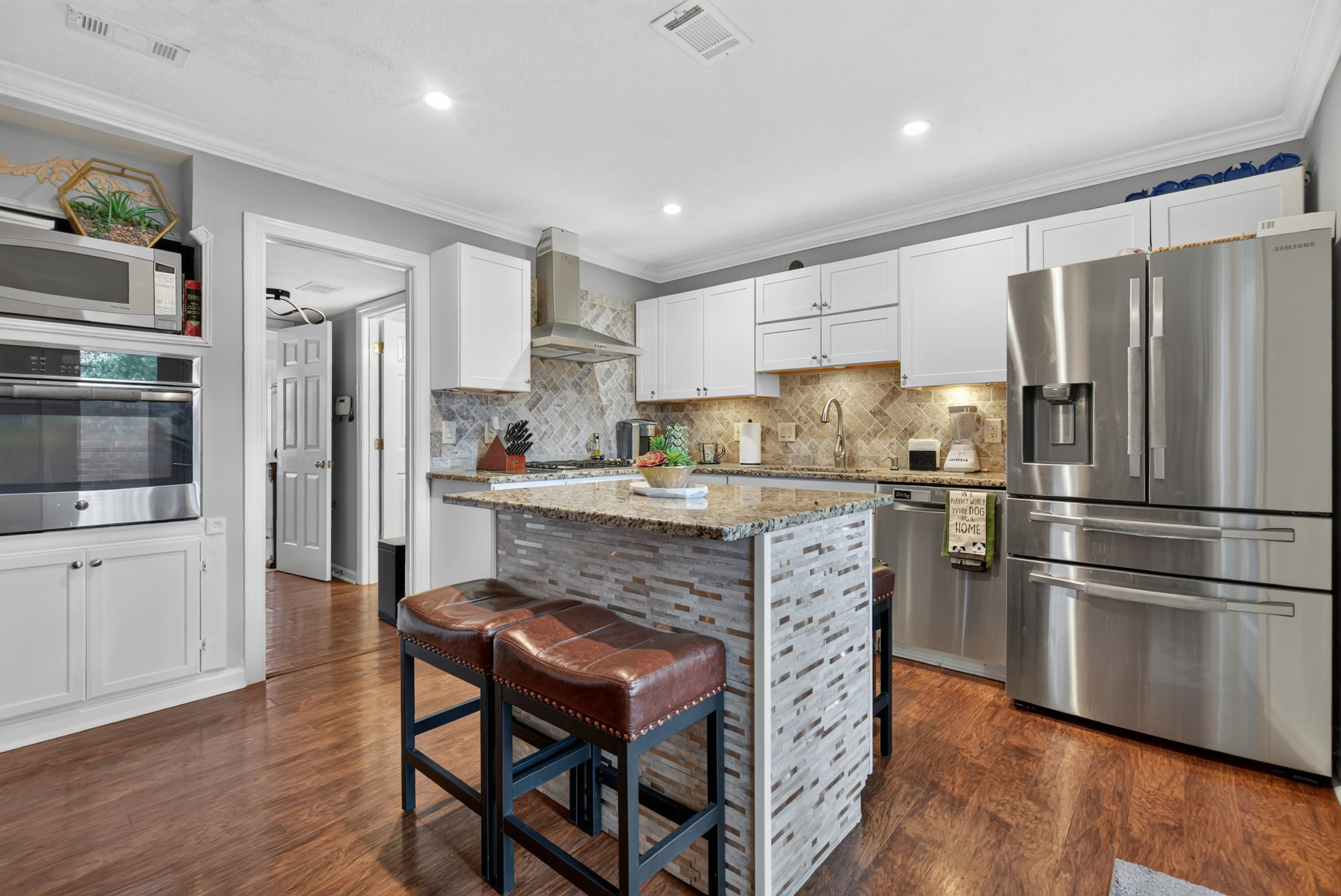 Kitchen with a stone island, white cabinets, and stainless appliances