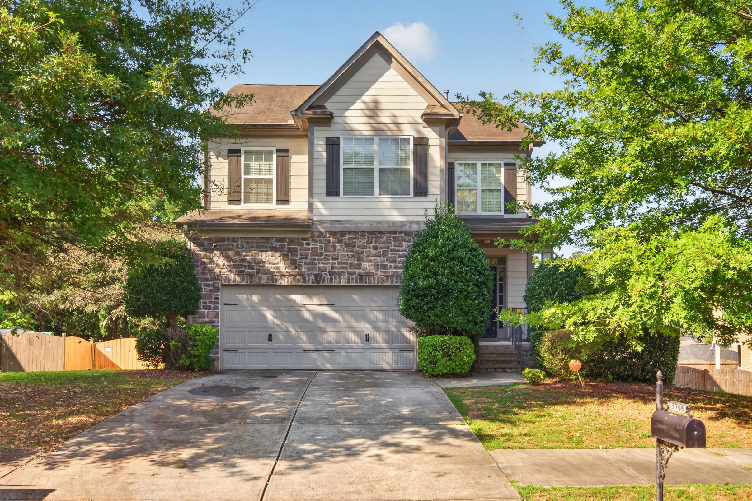 Two-story stone-front home with a double garage and mature trees