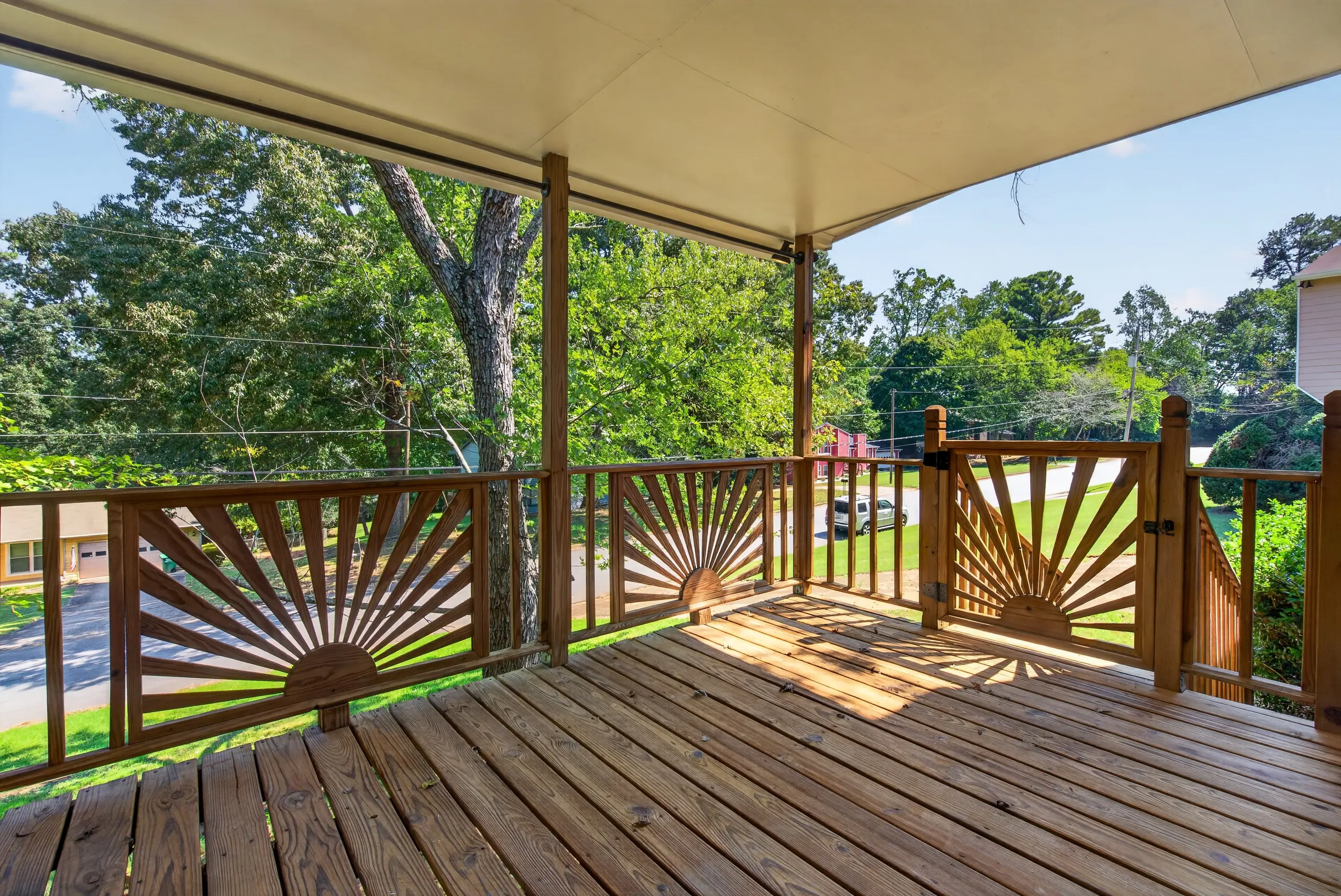 Covered wood deck with a sunburst railing overlooking the street