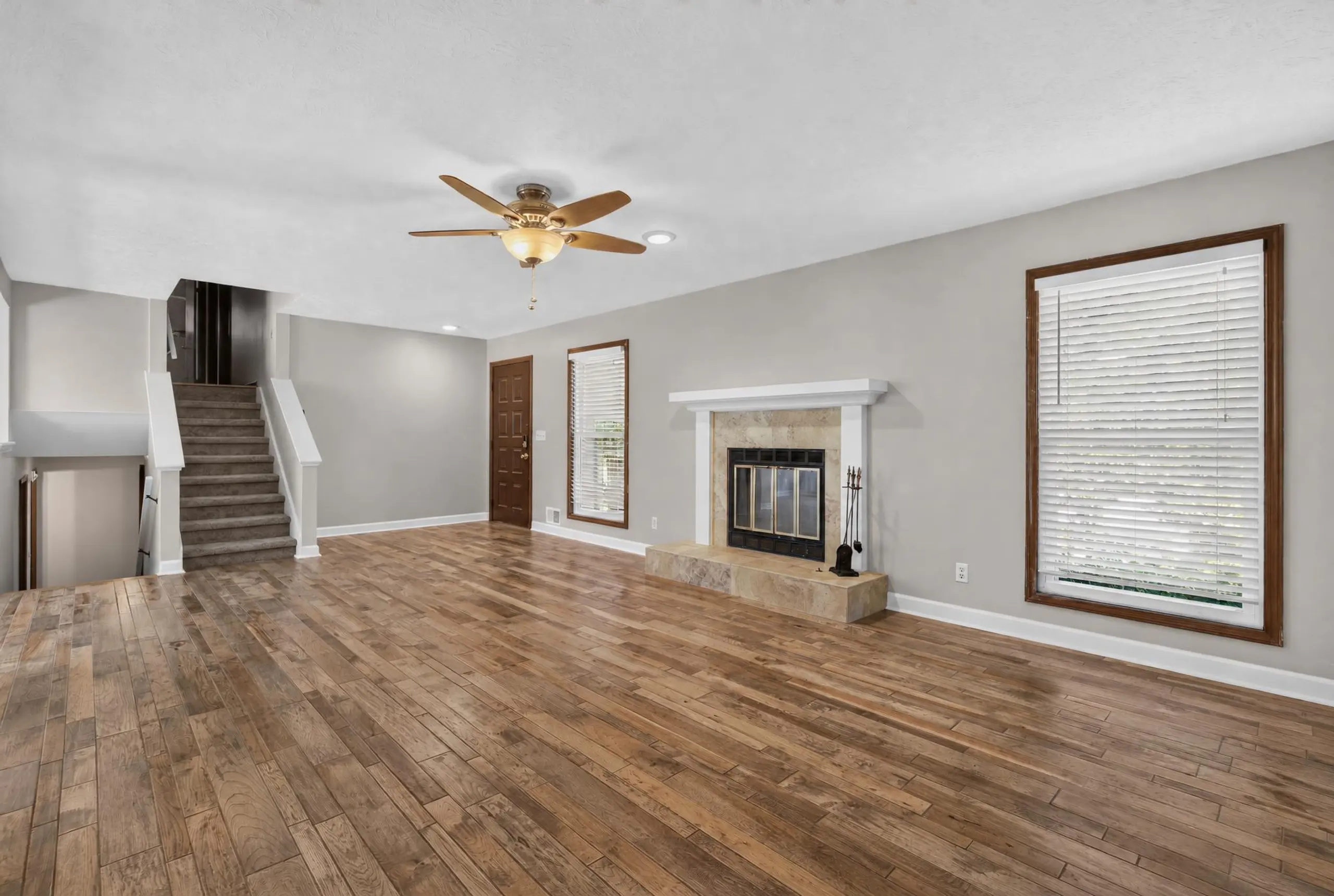 Living room with a fireplace, staircase, and wood-look floors